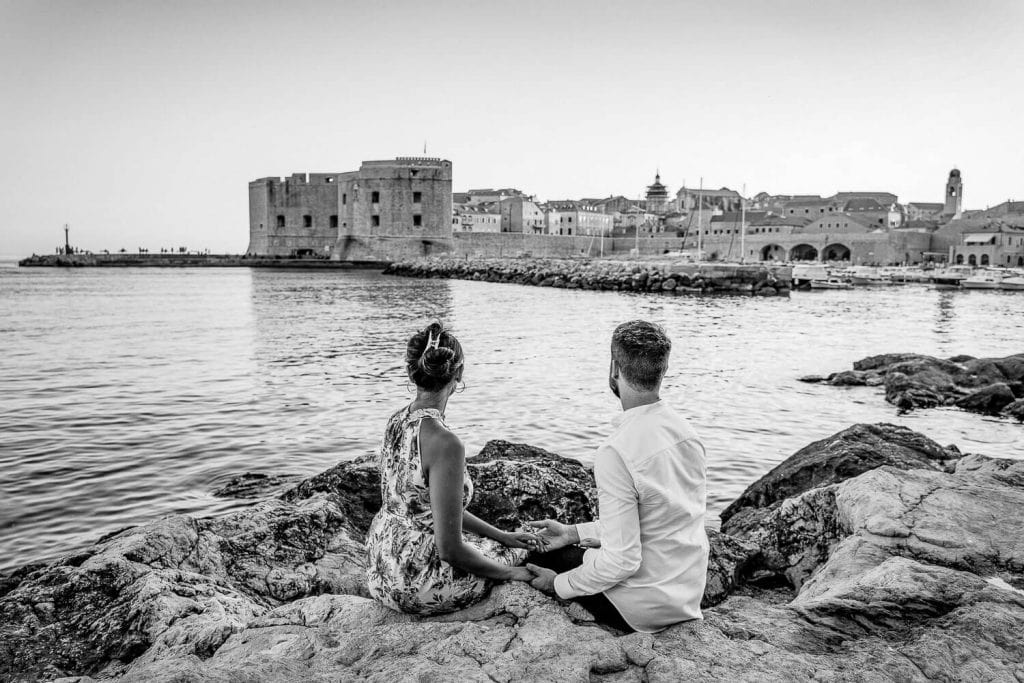 Couple in love looking at the Dubrovnik Old Town harbour while being photographed by a local photographer